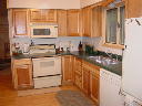 Kitchen. Window faces south. Includes stove, refrigerator, microwave, dishwasher, cookware, dishes, other small appliances.